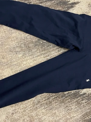 Mörkblå mjukisbyxor från Polo Ralph Lauren - Mörkblå mjukisbyxor från Polo Ralph Lauren med klassisk logga broderad på benet. Byxorna har resår i midjan, smal passform och en bakficka. Perfekta för chill dagar och riktigt sköna att ha på sig.