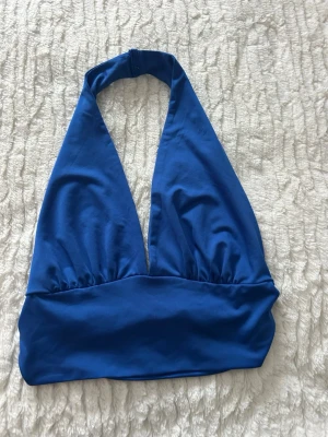 Blå topp  - Snygg blå topp   Toppens material känns mjukt och stretchigt, . Enkel och stilren design utan mönster eller extra detaljer.