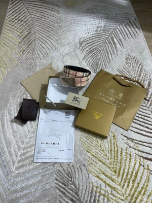  rutigt bälte med silverdetalj - Snyggt bälte  med klassiskt rutig design i beige, rött och svart. Bältet har ett stort silverfärgat spänne med  ingraverad. Perfekt accessoar för att lyfta din outfit med en lyxig touch.