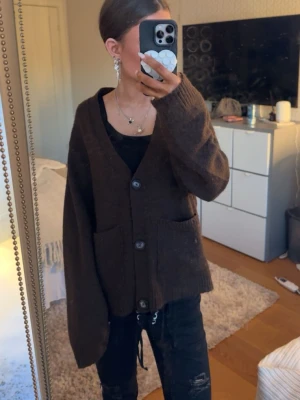 Brun kofta med fickor - Mysig brun kofta med v-ringning och stora knappar fram. Perfekt att slänga över en t-shirt eller linne för en avslappnad look.