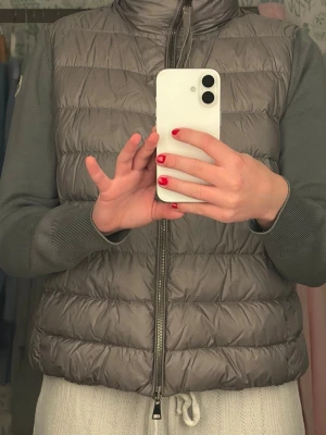 Grå dunväst från Moncler - Snygg grå dunväst från Moncler med quiltad design och hög krage. Västen har dragkedja framtill och diskret Moncler-logga på axeln. Köpt för 2 år sedan för cirka 8 000. I perfekt skick, inte använd många gånger.