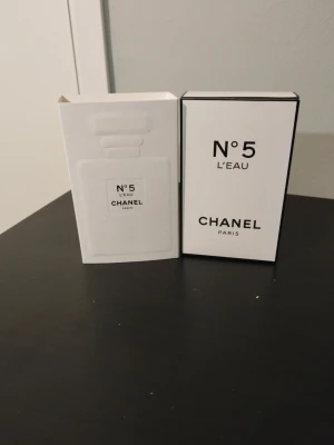 Chanel N°5 L'Eau Eau de Toilette - Chanel N°5 L'Eau Eau de Toilette i elegant vit och svart förpackning. Klassisk och stilren design med tydlig Chanel-logga och text. Parfymen är känd för sin fräscha och moderna tolkning av originalet, perfekt för dig som gillar exklusiva dofter.