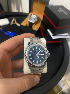 Silver analog klocka från Pagani Design - Stilren klocka från Pagani Design med blå urtavla, tydliga index och dag/datumvisning. Boett och länk i silverfärgat metall, sportig bezel och klassisk design. Perfekt accessoar för dig som gillar snygga detaljer.