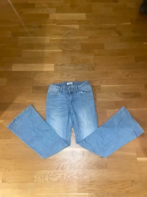 Ljusblå bootcut jeans - Säljer ett par ljusblå bootcut jeans med klassisk femficksdesign och hög midja. Jeansen har en snygg tvätt och raka, utsvängda ben. Perfekta till sneakers eller boots för en avslappnad look.