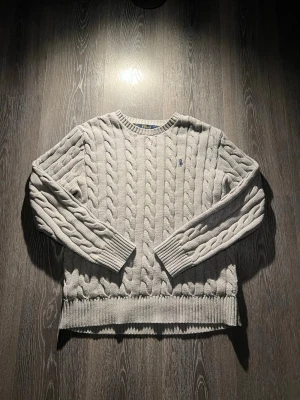 Ralph Lauren tröja - Grå Stickad Ralph Lauren sweater med RL loggan som passar för både finare och vardagstillfällen🙌. Den har inga defekter och är självklart äkta. I storlek M. Hör bara va er vid frågor fråga vad som helst så gör jag mitt bästa att svara 💯🙌