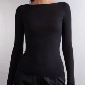 Svart långärmad topp - Snygg och stilren svart långärmad topp med tight passform. Perfekt för en minimalistisk look och kan enkelt matchas med olika outfits. Använd enstaka gånger.