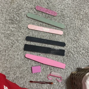 Nagelfilar I olika fätger - Ett set med nagelfilar i olika färger och texturer, inklusive glitter och pastellnyanser. Setet innehåller även en rosa nagelborste och en pincett. Perfekt för nagelvård och manikyr hemma.