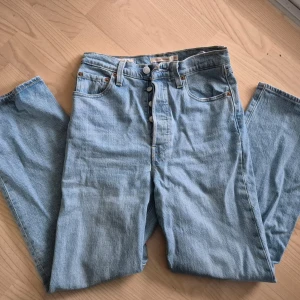 Levi's ljusblå jeans Ribcage straight - Säljer ett par klassiska Levi's Ribcage jeans i ljusblå denim. De har en straight passform och är högmidjade med knappgylf. Perfekta för en avslappnad stil. Endast använda ett fåtal tillfällen så fint skick! Storlek 25, osäker på benlängd men går till fotknölarna på mig som är 165cm lång. Skrynkliga efter tvätt och legat vikt.