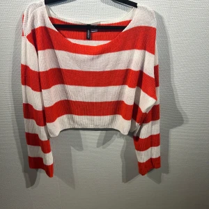 Randig röd och vit tröja från H&M Divided - Säljer en randig tröja från H&M Divided i rött och vitt. Tröjan är croppad och har långa ärmar med en ribbad struktur. Perfekt för en avslappnad stil.