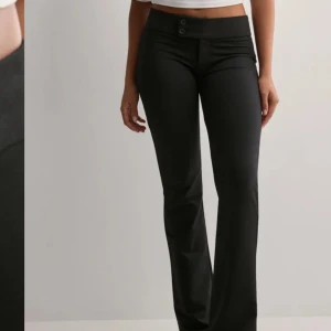 Svarta kostymbyxor med knappar - Snygga svarta kostymbyxor med låg midja och bootcut-stil. Byxorna har två knappar framtill💓 säljer då dom var för stora för mig, långa så passar bra om man är 173 men även kortare. Knappt använda