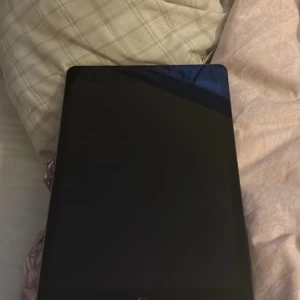 iPad med 32 GB lagring - Säljer en iPad med 32 GB lagringskapacitet. Den har en svart framsida och en grå baksida med Apple-logotypen. 