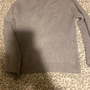 Grå stickad tröja - Säljer en stilren grå stickad tröja med långa ärmar. Perfekt för kyligare dagar och enkel att matcha med olika outfits. Tröjan har ribbstickade muddar vid ärmslut och nederkant. Nytt pris 399 säljer för 95kr
