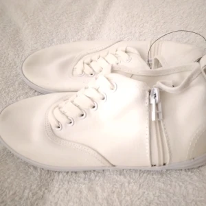 HELT NYA & OANVÄNDA höga sneakers från Divided / H&M, vit / vita, 36. - Helt nya, oanvända och felfria höga vita sneakers från H&M Divided. Tags/prislapp sitter kvar. Skorna har snörning fram och en dragkedja på varje sida. Smidiga/lätta att ta på och av. Snygga och perfekta för våren/sommaren. Skickas inplastade I originalförpackning. Storlek: 36. Material: tyg, troligen canvastyg.