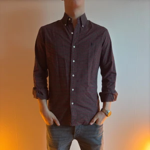 Ralph Lauren skjorta - Snygg rutig skjorta från Ralph Lauren i mörka toner. Skjortan har långa ärmar och klassisk krage med knappar framtill. Perfekt för en stilren look.