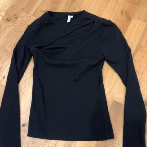 Svart långärmad topp från NLY Trend - Snygg svart långärmad topp från NLY Trend med unik asymmetrisk design vid halsen. Storlek S