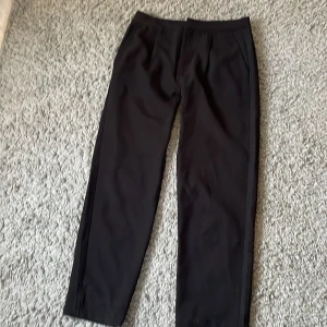 Svarta kostymbyxor från 157 - Snygga svarta kostymbyxor från 157 i storlek M. Byxorna har en klassisk rak passform och är perfekta för en stilren look. De är tillverkade i ett bekvämt material som ger en elegant känsla.