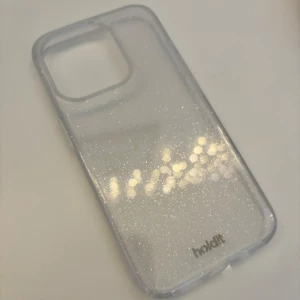 iPhoneskal från Holdit  - Ett iPhoneskal till 15 Pro från Holdit 💞Genomskinligt med glitter ☺️ Aldrig använt och skyddsplasten är fortfarande på! Saknar dock förpackningen! Säljer då jag köpte fel 🥹Originalpris: 299kr