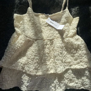 Vit linnetopp  - Gräddvit linnetopp från Gina Tricot med smala och justerbara axelband i ett krinklat material, aldrig använd med prislappen kvar.