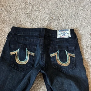 Skitsnygga True Religon jeans - Jätte snygga och unika True religon jeans i väldigt bra skick. Midjemåttet tvärsöver är 35 cm och innerbenslängden är 89 cm. Jeansen passar någon som har storlek XXS-XS dock är dom långa i benen så passar någon som är lång. Jag på bilden är 168 cm lång