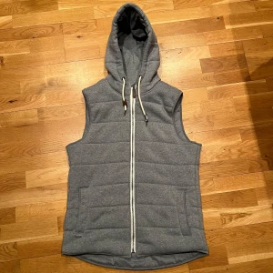 Grå väst med huva från Denim Day - Säljer nu min väst från Denim Day. Västen har en dragkedja framtill och snören vid huvan. Perfekt nu till våren när vädret börjar bli lite varmare. Hör av er vid minsta fråga🙌