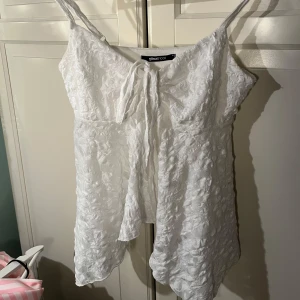 Vit spetslinne från Gina Tricot - Säljer ett sött vitt spetslinne från Gina Tricot med smala axelband och knytning framtill. Perfekt för varma dagar med sitt luftiga och lätta material. Linnet har en vacker struktur och en feminin touch. Använd 1 eller 2 gånger, perfekt/nytt skick. Pris går att diskutera💕