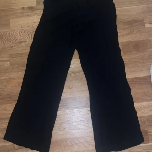 Svarta byxor från Stradivarius - Snygga svarta linne byxor från Stradivarius i en loose passform. Perfekta för en avslappnad stil med hög komfort. Tillverkade i ett mjukt material som ger en skön känsla hela dagen. Storlek S.