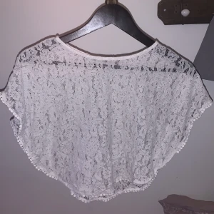 Vit spetsblus för barn - Säljer en söt vit spetsblus för barn från H&M. Blusen har ett vackert spetsmönster och korta ärmar. Perfekt för somriga dagar eller speciella tillfällen. 🕊️