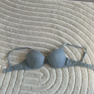 Ljusblå spets-BH från H&M med lite push - Säljer en elegant grå BH från H&M med spetsdetaljer. Den har justerbara axelband och en klassisk knäppning där bak. Bhn har lite push up och är använd fåtal gånger🩵