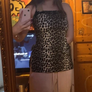 Leopardmönstrad linne med spetsdetaljer - Snygg leopardmönstrad linne med smala axelband och spetsdetaljer vid halsringningen. Perfekt för en trendig look. passar s-m