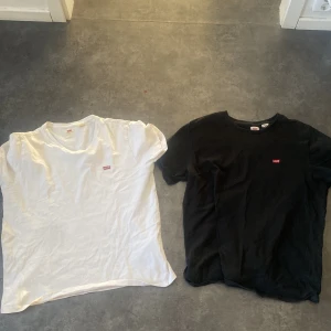 Svart och vit t-shirt från Levi's båda två för endast 250 - Två klassiska t-shirts från Levi's i svart och vitt. Båda har en liten röd Levi's-logga på bröstet. Perfekta basplagg för garderoben. Tillverkade i mjuk bomull för en bekväm passform.