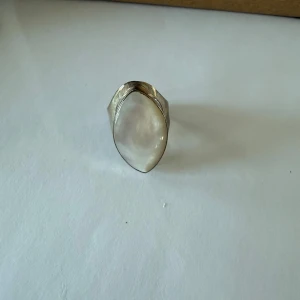 Silverring med pärlemor - Elegant silverring med en stor pärlemorsten i centrum. Ringen har en stilren design som framhäver stenens naturliga skönhet. Perfekt för att ge en touch av elegans till din stil.