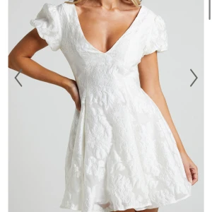 Vit kortklänning med puffärmar - Säljer en söt vit kortklänning med puffärmar och v-ringning. Klänningen har ett vackert blommigt mönster och en öppen rygg som ger en elegant touch. Perfekt som studentklänning och till sommarens alla tillfällen!🙌🏼 Köpt från Showpo för 1400kr inklusive frakt och aldrig använd! 💞Skriv privat för fler bilder!