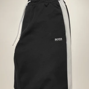 Hugo Boss byxor - Säljer dessa snygga byxorna från Hugo Boss i storlek M. Lite tajtare i passformen men annars riktigt snygga. Liknar de populära Palm Angels byxor med samma vita rand på sidorna av benen. Byxorna är i mycket bra skick utan synliga defekter. Mitt pris: 399, priset är dock diskutabelt. Hör gärna av er med frågor eller liknande!