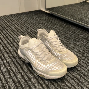Vita Nike sneakers med rutigt mönster - Säljer ett par vita Nike sneakers i bra skick. De har ett coolt rutigt mönster och klassisk snörning. Perfekta för både vardag och träning. Skorna har en bekväm passform och är lätta att matcha med olika outfits.