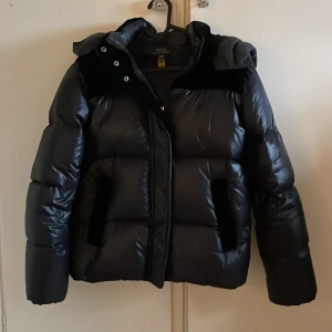 Svart pufferjacka från Polo Ralph Lauren  - Säljer en snygg svart pufferjacka från Polo. Jackan har en dragkedja framtill och luva. Den är i ny skick och endast använd ett fåtal gånger. 