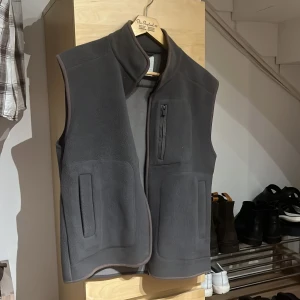 Grå fleeceväst från Dobber - Säljer en grå fleeceväst från Dobber i storlek S. Västen har en dragkedja framtill och en bröstficka med dragkedja. Perfekt för lager-på-lager under höst och vår. Den är i mycket bra skick och supermjuk. Stor i storleken för att vara en S