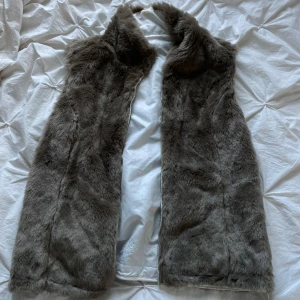 Vändbar pälsväst vit/brun  - Säljer en supermysig grå pälsväst med en stilren vit insida. Västen har en dragkedja framtill och är perfekt för höst och vinter. Den är i nytt skick och passar både till vardags och fest. Perfekt för att hålla sig varm och snygg!
