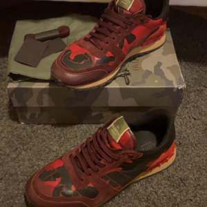 Säljer ett par snygga Valentino Rockrunner sneakers i röd och svart camouflage. De har en cool design med snörning och är i mycket bra skick. 