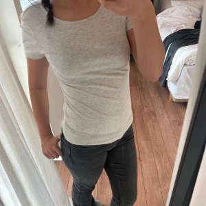 Grå ribbad t-shirt - Säljer en enkel och stilren grå ribbad t-shirt i storlek S. Den är kortärmad och har en tight passform, perfekt för vardags eller som basplagg. Superbekväm och lätt att matcha med allt! Orginalpris är 199kr