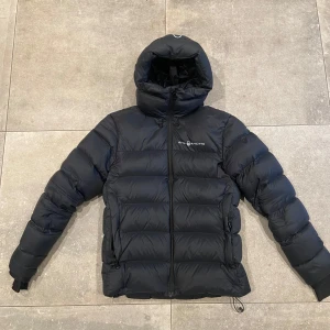 Svart dunjacka från Sail Racing - Säljer en svart dunjacka från Sail Racing i storlek S. Jackan är i mycket bra skick och perfekt för kalla vinterdagar. 