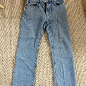 Blå jeans från Voyage - Säljer ett par klassiska blå jeans från Weekday i mycket bra skick. De har en straight passform och är perfekta för vardagsbruk. Jeansen har en dragkedja och knapp framtill samt fem fickor. Perfekta för både vår och höst!