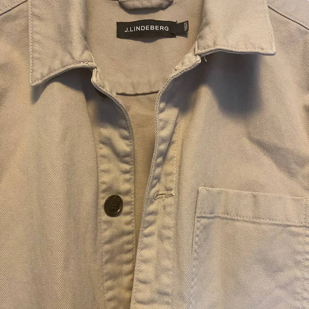 Säljer en snygg beige overshirt från J. Den har en klassisk krage med knappar framtill. Materialet känns slitstarkt och bekvämt. Passar både till vardags och lite finare tillfällen. Storlek L och passar dig som är runt 185cm.. Jackor.