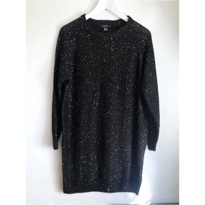 Svart lång stickad tröja, paljetter, M 40/42, miniklänning, silver, fest, party - Lång stickad svart tröja med små silverfärgade paljetter, raglanärm. Finns några dragna trådar. Storlek (EU): M, bröstvidd: 54,5 cm, längd fram från axeln: 79,5 cm, ärmlängd mätt från halsen: 67,5 cm.