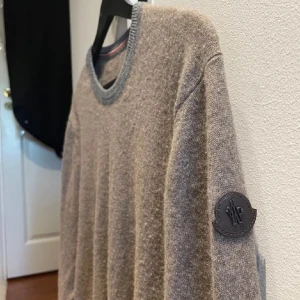 Moncler Kashmir tröja - Moncler tröja i 100%  kashmir. Tröjan är i bra skick bortsett från en liten lagning efter att en tråd lossnat. Lagningen syns bara på insidan av tröjan (bild 4 utsida och 5 insida). Storleken är XL men sitter som L. Nypris ca 7000