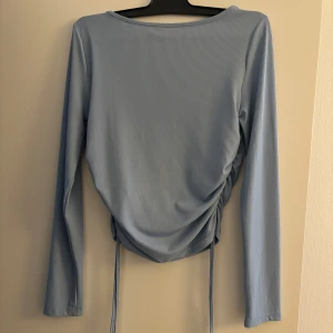 Ljusblå ribbad topp - Säljer en superfin ljusblå ribbad topp med långa ärmar. Den har en snygg snörning i sidan som ger en cool effekt och gör den lite croppad. Perfekt för både vardag och fest! 💙