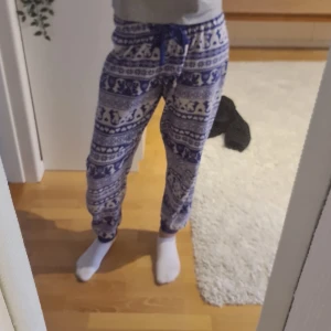 Mönstrade mjukisbyxor från Love to Lounge - Supermysiga mjukisbyxor från Love to Lounge i storlek S. De är blå och vita (vissa kan se lila) med ett snyggt mönster som ger en härlig vinterkänsla. Perfekta för att chilla hemma eller ha på sig under kalla dagar. Byxorna har en bekväm passform och är gjorda i mjukt material.
