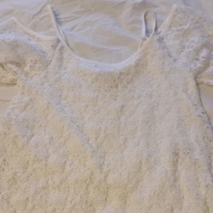 Vit spetsblus från Gina Tricot - Säljer en superfin vit spetsblus från Gina Tricot i storlek XS. Den har en söt offshoulder-design med korta ärmar och är perfekt för sommaren. Blusen är i ett härligt spetsmaterial som ger en romantisk känsla. Perfekt för både vardag och fest!