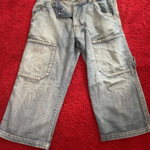 Baggy jeans med stora fickor - Säljer ett par baggy jorts från WPM i storlek 46. De är ljusblå och har stora fickor på sidorna, perfekt för en avslappnad stil. Jortsen har en lös passform och är gjorda i denim, vilket gör dem både bekväma och slitstarka.