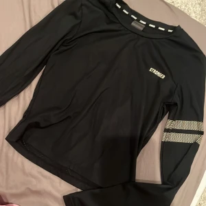 Tränings tröja  - Jättefin tränings tröja ifrån stronger som är använd cirka 2 gånger den är i nyskick. Säljer då den är för liten. Köpt för 599. Jättefin med guldiga detaljer
