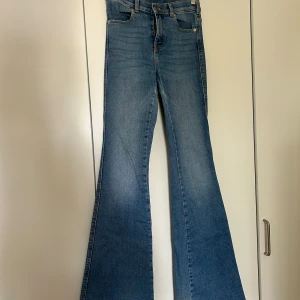 Blå bootcut jeans från Dr. Denim - Säljer ett par snygga blå bootcut jeans från Dr. Denim i storlek S/34. De har en klassisk fyrficksdesign och är perfekta för både vardag och fest. Jeansen är i bra skick och har en skön passform som sitter snyggt över höfterna och vidgar sig vid benen. Nypris 700kr